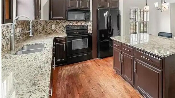 A modern kitchen with dark cabinetry, a granite countertop, and stainless steel appliances. - Downtown Atlanta Anchor (Atlanta)