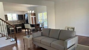 A spacious living room with a grey sofa, a glass coffee table, and a staircase leading to another level. - Downtown Atlanta Anchor (Atlanta)
