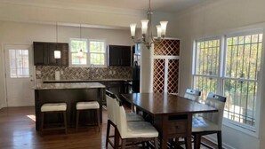 A spacious kitchen with a central island, bar stools, and a dining table with chairs. - Downtown Atlanta Anchor (Atlanta)
