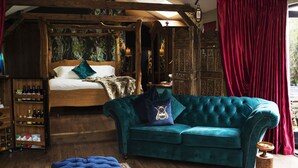 A cozy room with a wooden bed, a teal sofa, and a blue ottoman. - Romantic Lodge on Edge of Nature Reserve (Colchester)