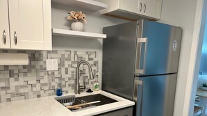 A modern kitchen with a stainless steel refrigerator, a built-in dishwasher, and a tiled backsplash. - Totally Renovated 1BR/1BA/All New Furniture/Sofa Bed/Balcony/Walk-In Shower/WiFi (Hilton Head Island)