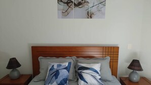 Un lit bien fait, avec deux oreillers, une tête de lit en bois et deux tables de chevet avec des lampes.