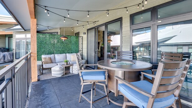 A modern outdoor dining area with a round table, chairs, and string lights. - Downtown Winter Park Condo: Steps to Everything! (Winter Park)