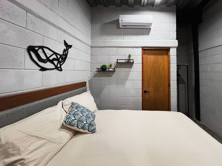 Una camera da letto con un letto, una porta in legno, un condizionatore d'aria a parete e un elemento decorativo al muro.