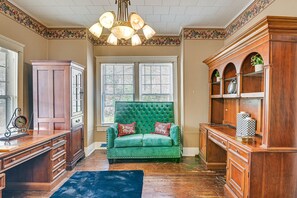 Una habitación con un sofá de terciopelo verde, armarios de madera y un candelabro.