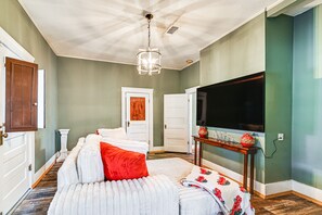 Un dormitorio con una cama grande, televisión y una puerta que da a otra habitación.