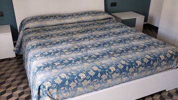Een slaapkamer met een bed, nachtkastjes en een vloer met patroon.