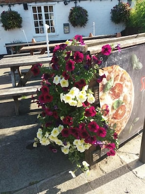 A flower arrangement with a pizza advertisement on a wooden bench. - The Maidens Chambers (Canterbury)