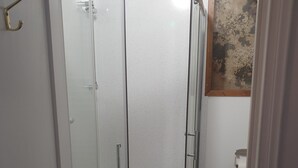 Eine Duschkabine mit Glas, einer weißen Tür und einem Holzrahmen.