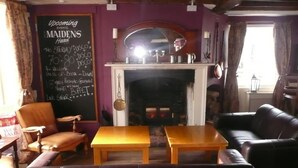 Una habitación con chimenea, una pizarra con información sobre eventos y un sofá de cuero.