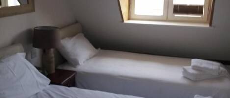 A room with two beds, a window, a lamp, and a mirror.