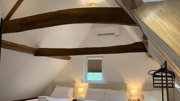 A room with two beds, a window, and a ceiling with exposed wooden beams.