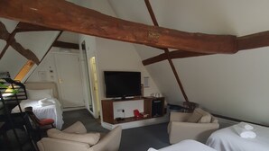 Ein Zimmer im Dachgeschoss mit zwei Betten, einem Fernseher, einem Schreibtisch und einem Stuhl.