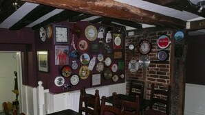 Un comedor con una pared de ladrillo decorada con relojes y un ventanal con marco blanco.