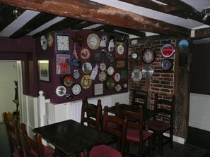 Un comedor con una pared de ladrillo decorada con relojes y un ventanal con marco blanco.