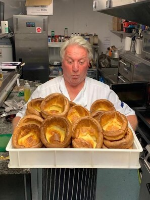 Una persona sosteniendo una bandeja de productos horneados en una cocina.