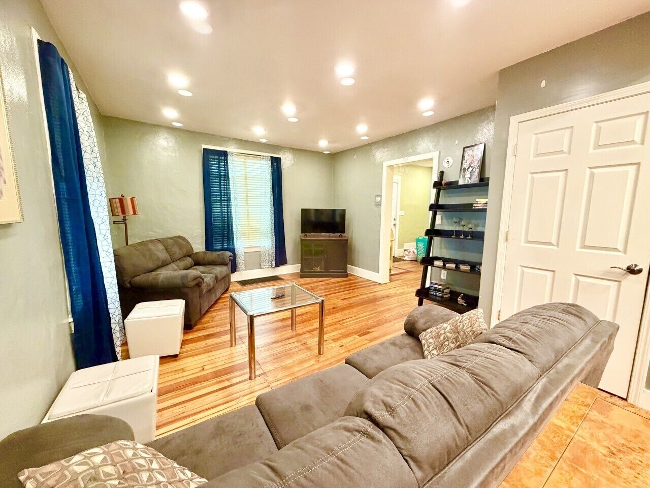 A living room with a sofa, a coffee table, a television, and a bookshelf.