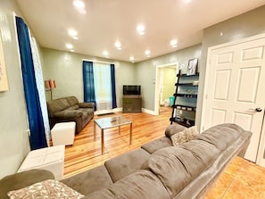 A living room with a sofa, a coffee table, a television, and a bookshelf. - Spacious Home in Johnson City, NY by BU, UHS & BCC (Johnson City)