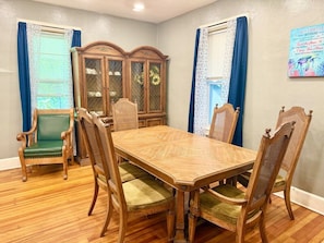 A dining room with a wooden table and chairs, a cabinet, and blue curtains. - Spacious Home in Johnson City, NY by BU, UHS & BCC (Johnson City)