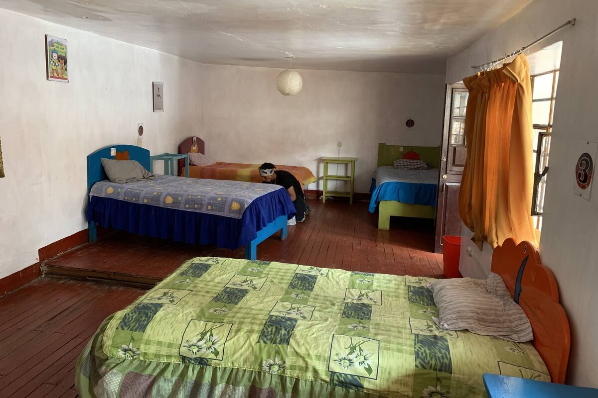 A room with two beds, a small table, and a window with curtains.