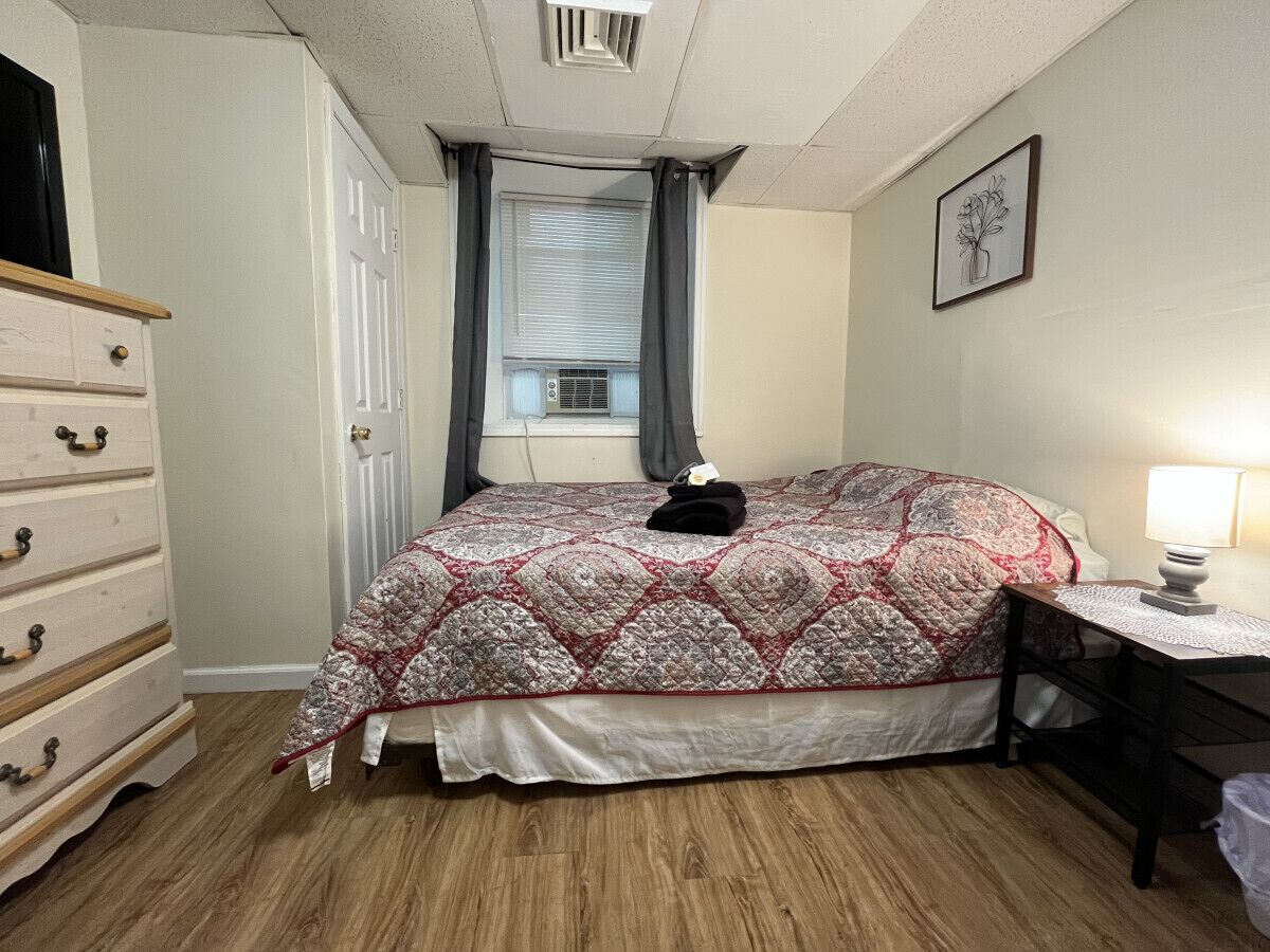 A bedroom with a bed, a dresser, a desk, and a window with curtains.