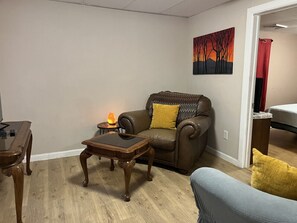 Een woonkamer met een leren bank, een houten salontafel en een bijzettafeltje met een lamp.
