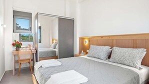 A bedroom with a bed, a desk, a chair, a mirror, and a window. - Theseus Villa (Chania Town)