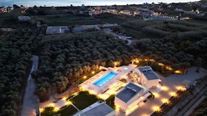 A modern building with a swimming pool, surrounded by trees and well-lit pathways. - Theseus Villa (Chania Town)