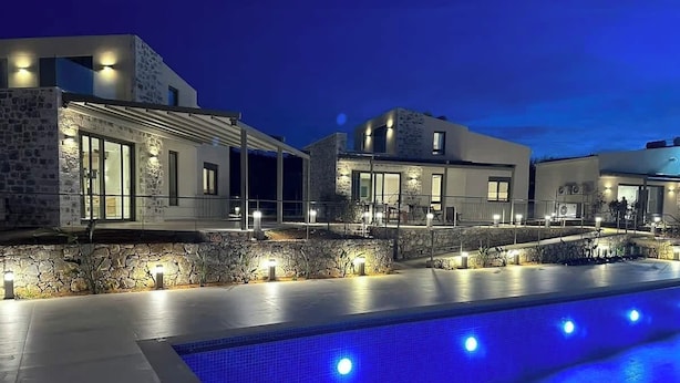 A modern hotel with a swimming pool, stone facade, and outdoor lighting. - Theseus Villa (Chania Town)