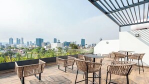 A rooftop terrace with wicker furniture and a city view. - Brand-New Penthouse with Private Terrace (Ciudad de México)