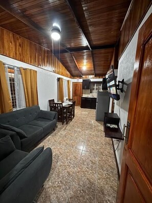 Habitación con sofá, mesa de comedor y zona de cocina con armarios y refrigerador.