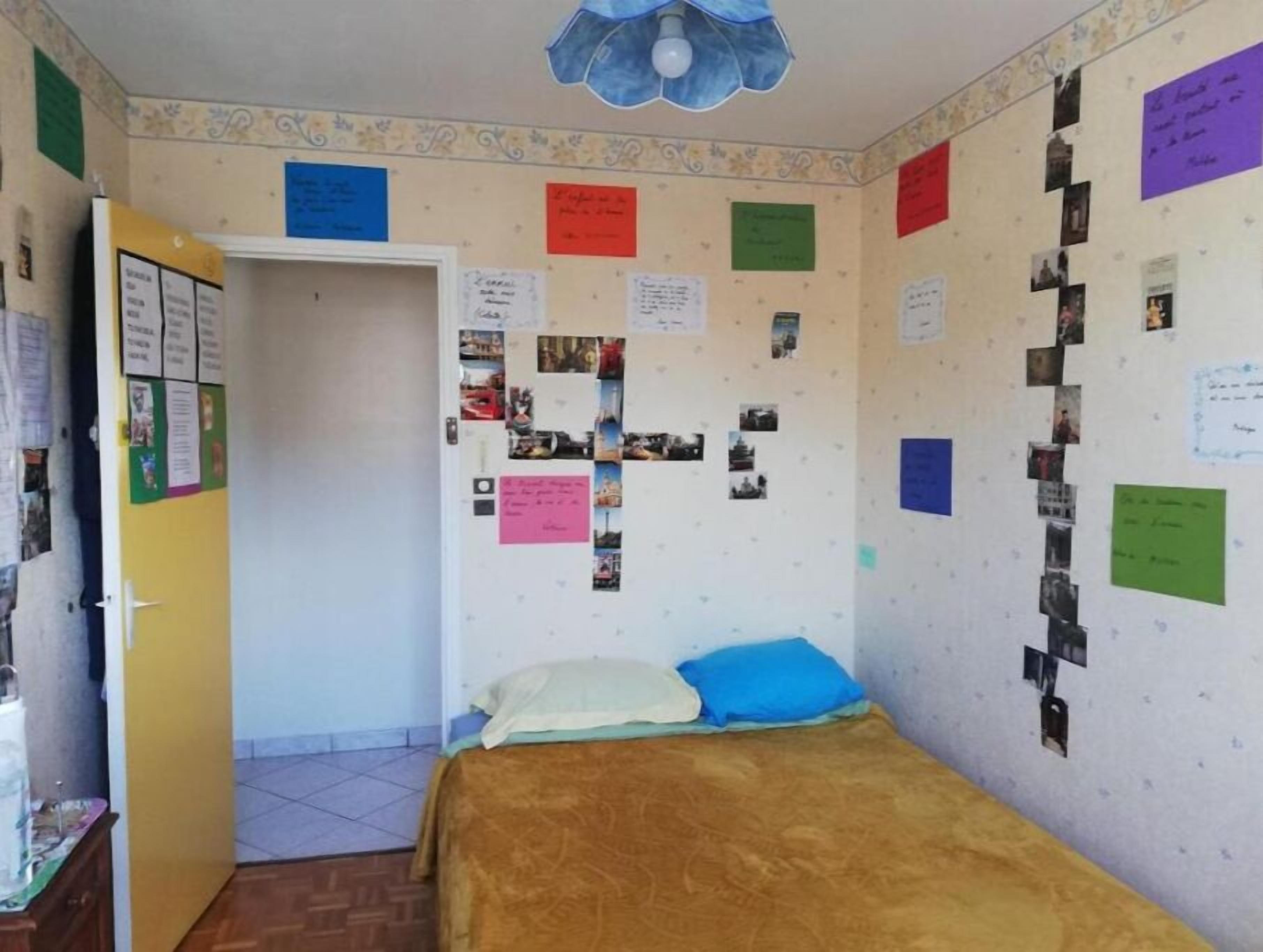 Ein Schlafzimmer mit einem Bett, einer Tür und Wänden, die mit Fotos und Notizen bedeckt sind.
