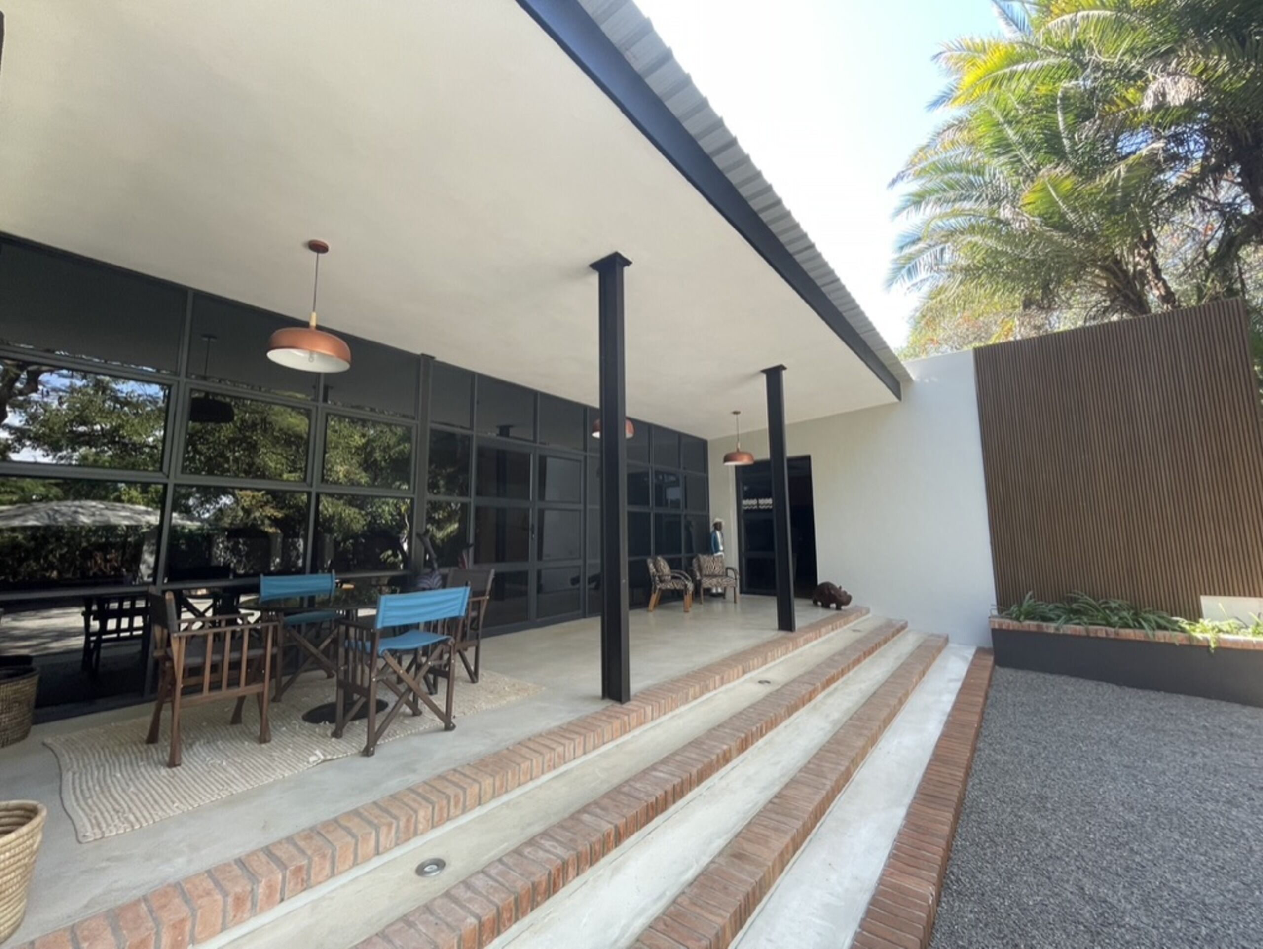 A covered outdoor area with a patio, seating, and a staircase leading to a door.