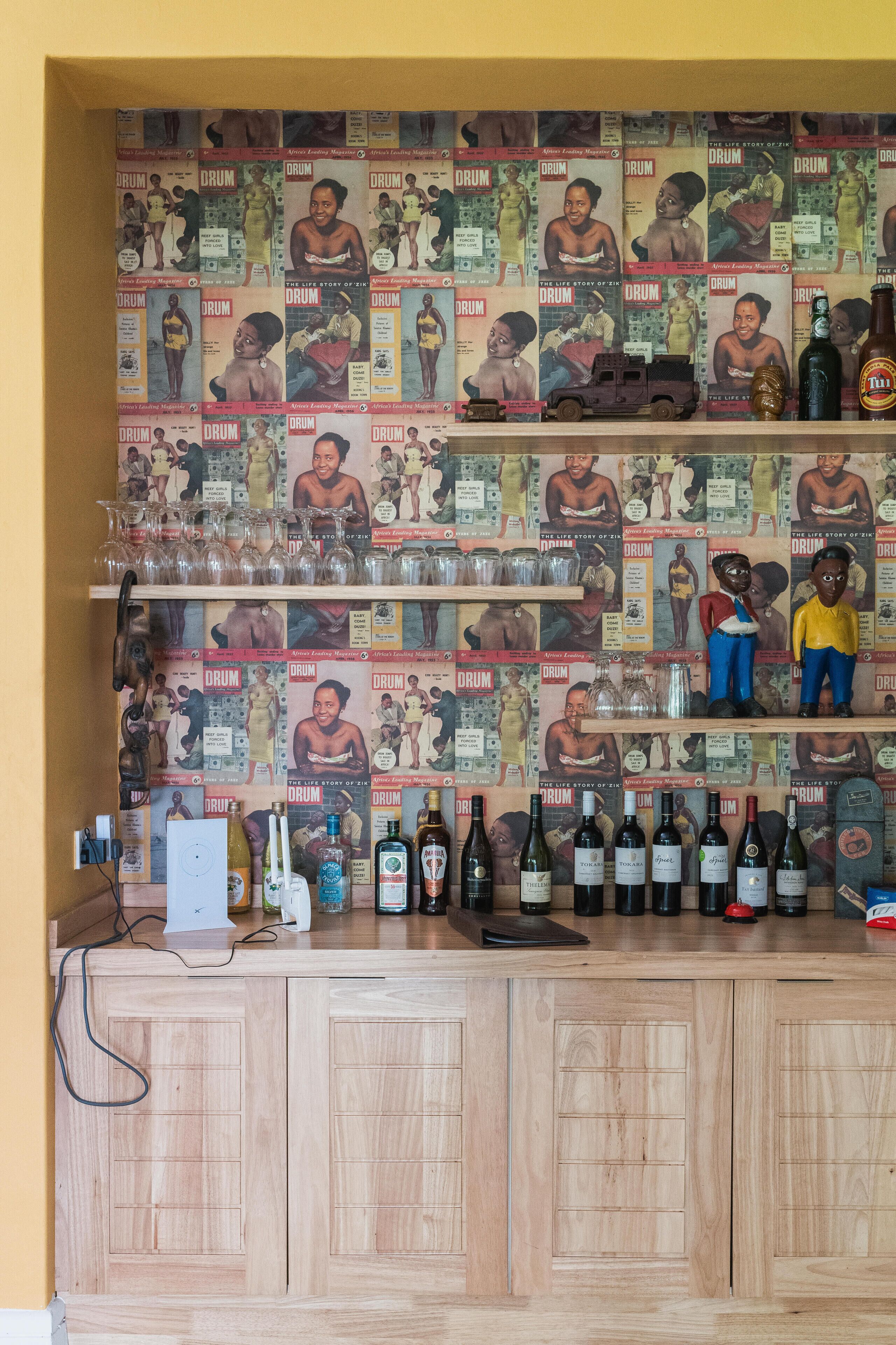 A bar with wooden cabinets and shelves displaying various bottles.