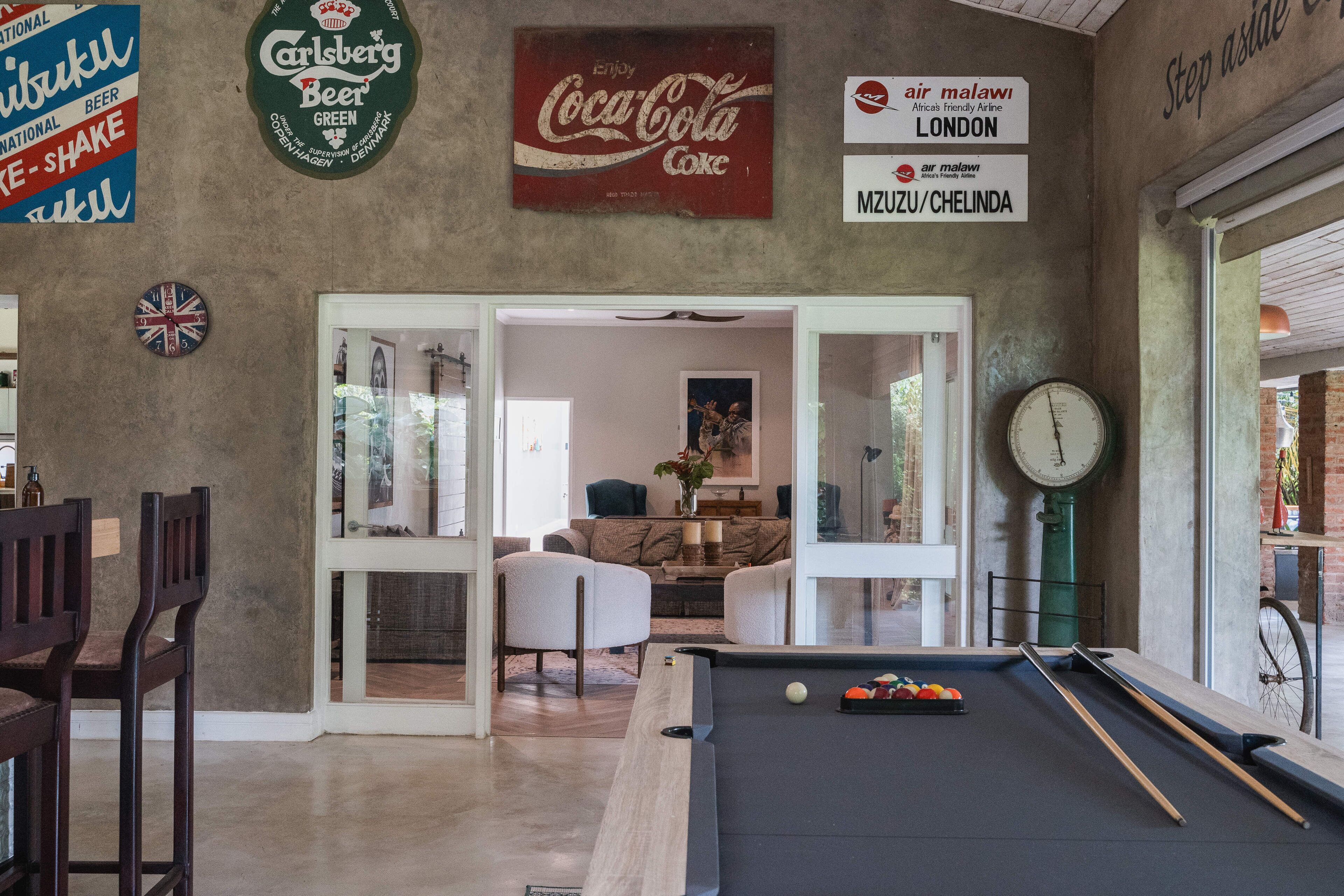 Une table de billard, un canapé et une porte donnant sur un salon.