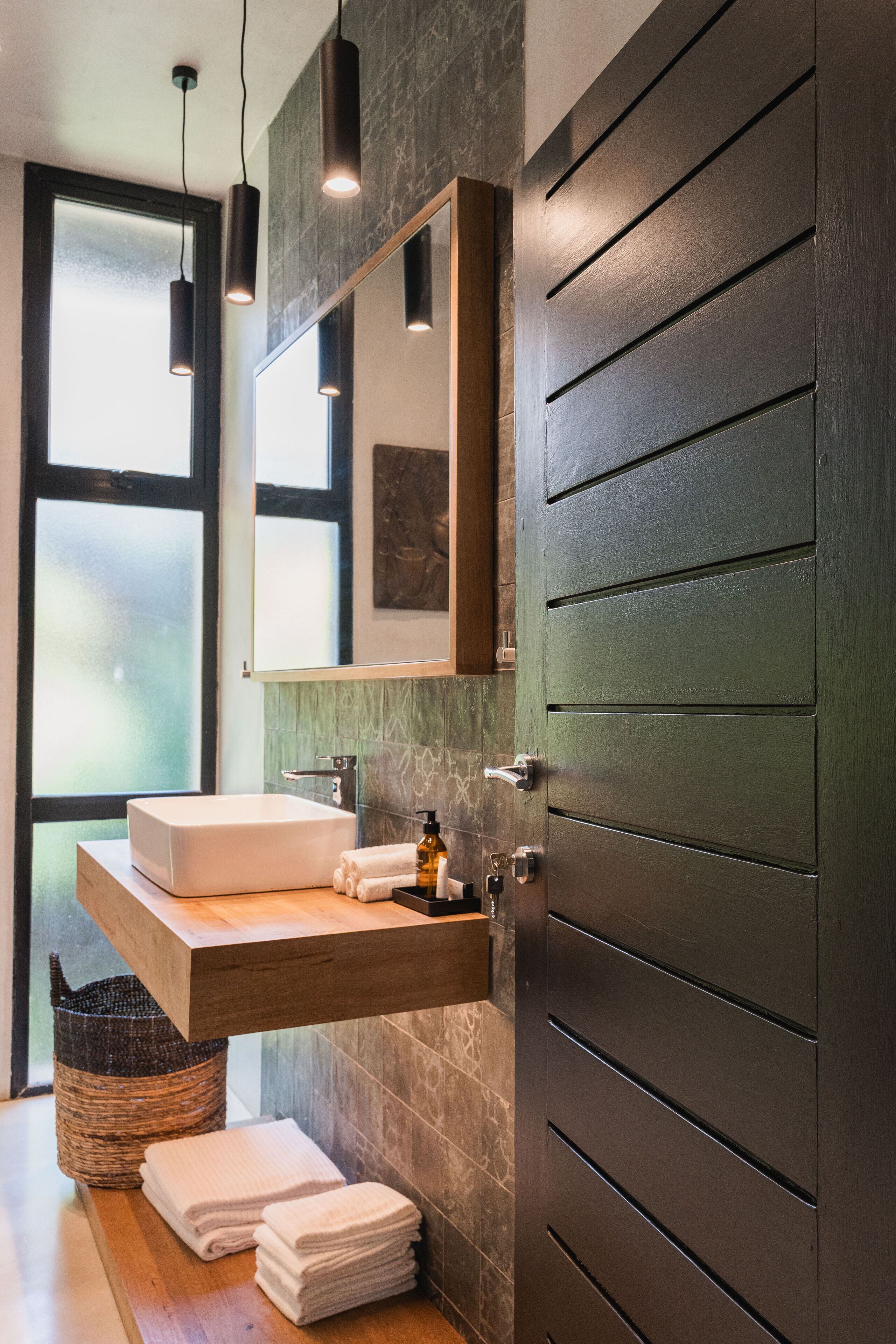 A modern bathroom with a large mirror, a wooden vanity, a sink, and a towel rack.