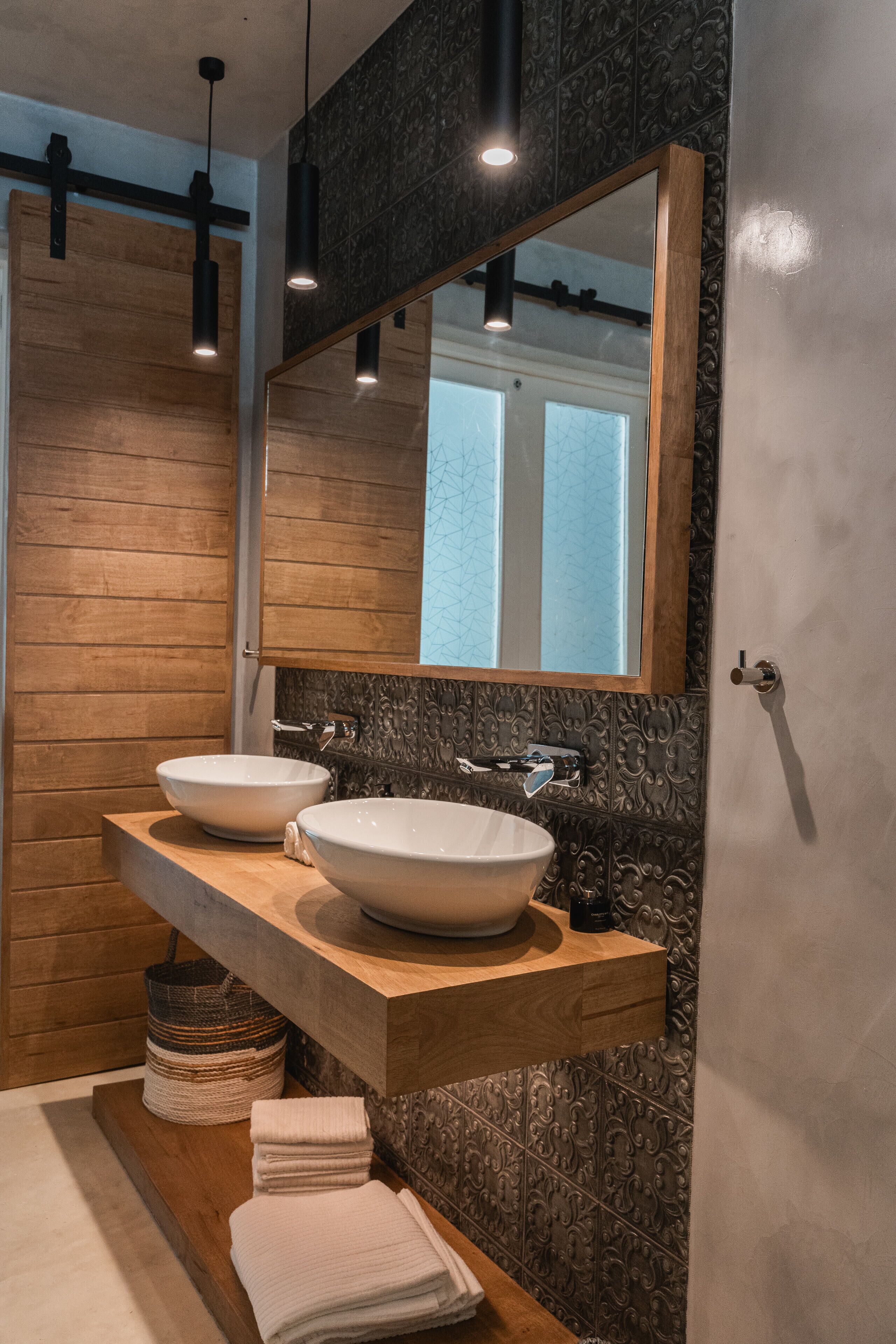 A modern bathroom with two sinks, a wooden vanity, and a large mirror.