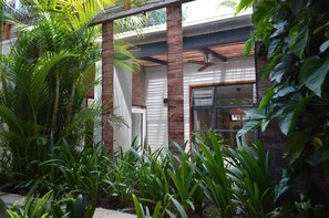 Un bâtiment moderne aux éléments en brique et en verre, entouré d’une végétation luxuriante.