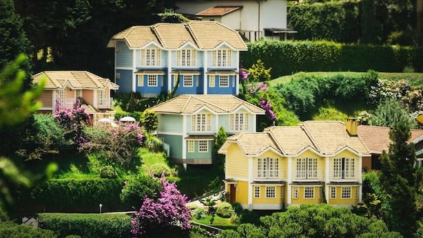 Maqueta de una zona residencial con varias casas, cada una de un color diferente y rodeada de jardines cuidados.