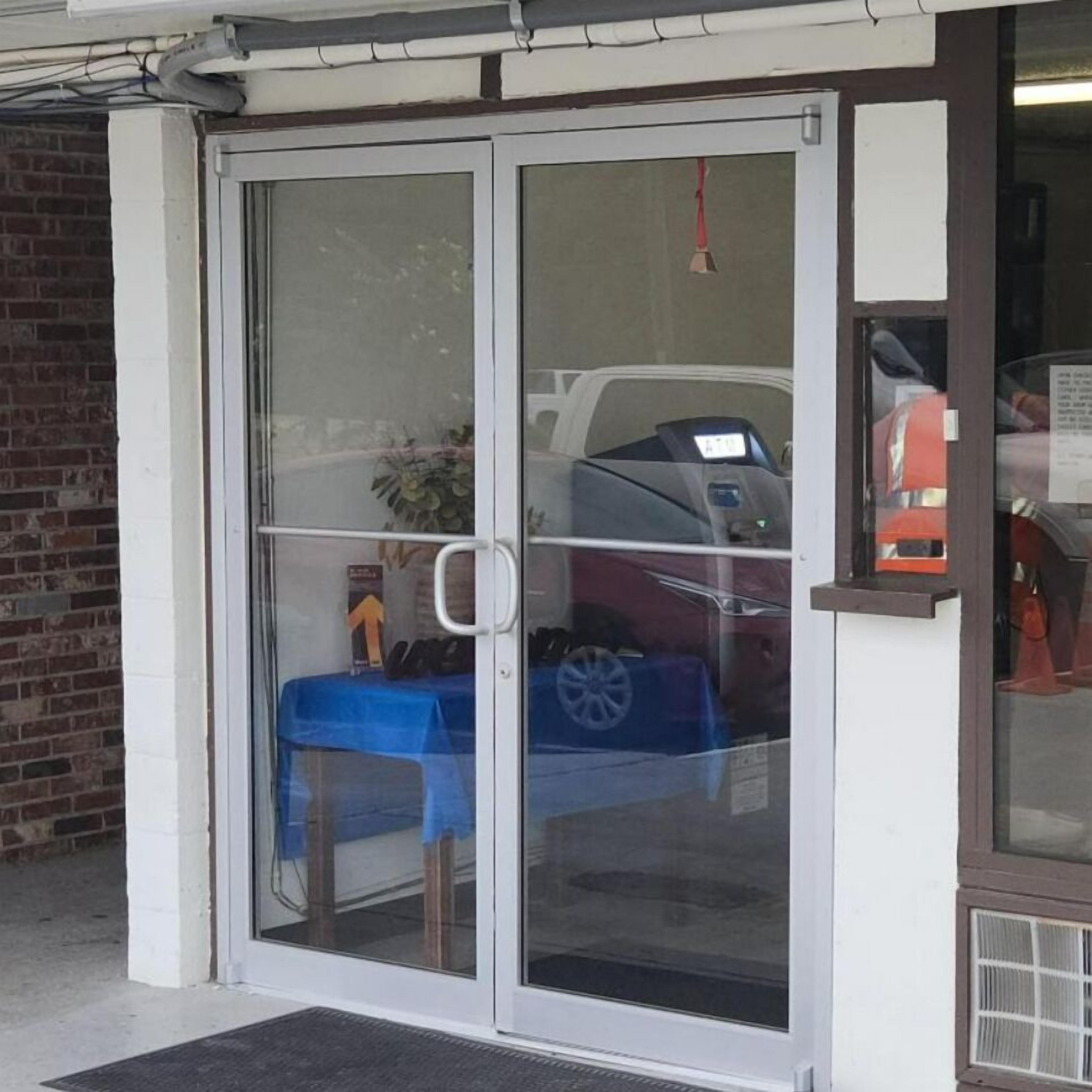 A building entrance with a glass door, a blue table, and a car inside.