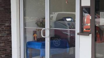 A building entrance with a glass door, a blue table, and a car inside.