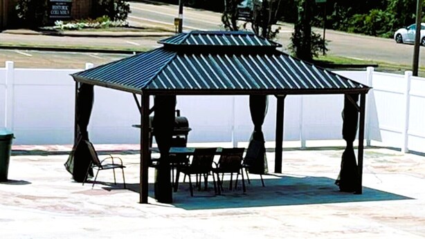 Ein Kiosk mit Metalldach und vier Stühlen.