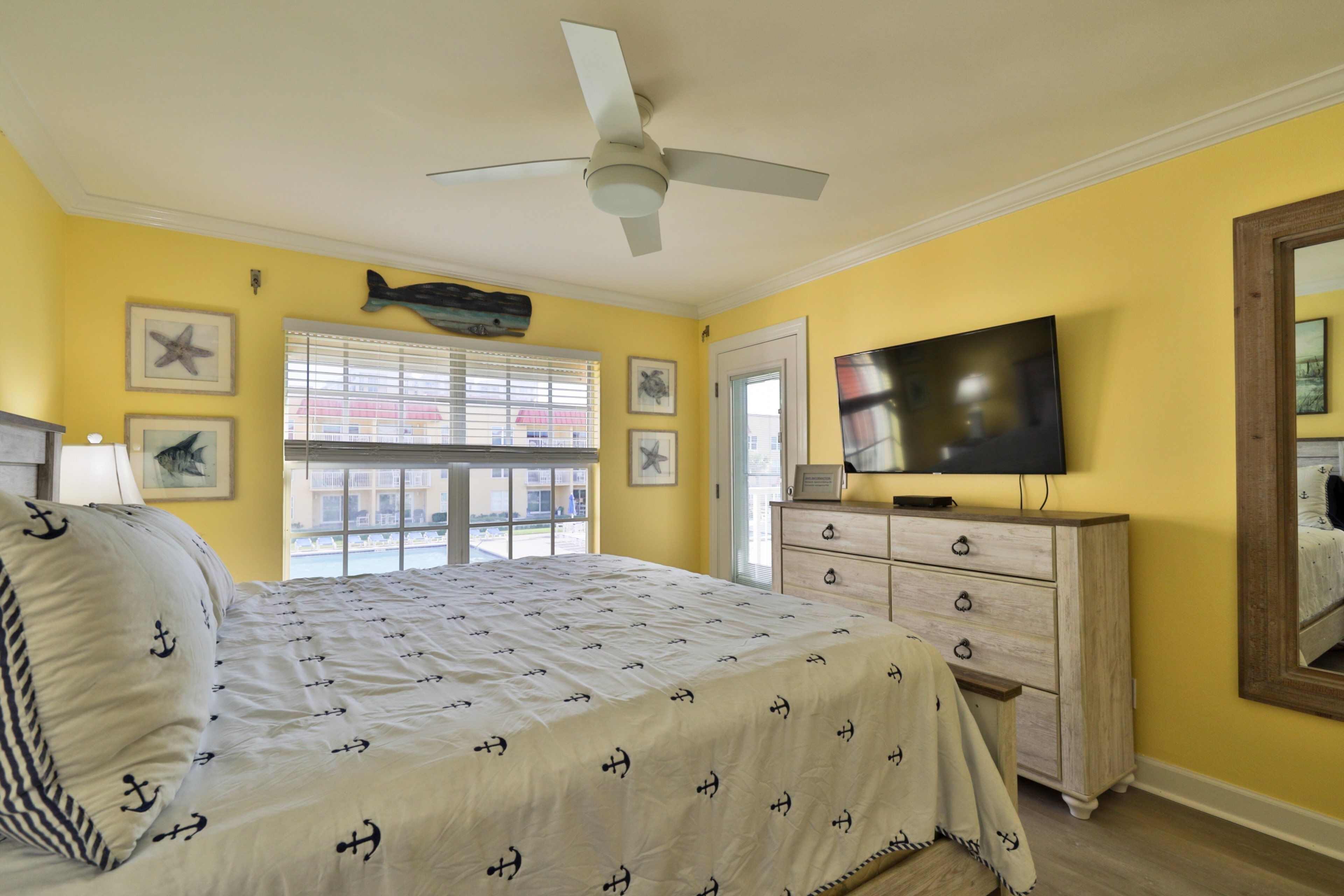 A bedroom with a bed, a dresser, a television, and a ceiling fan.