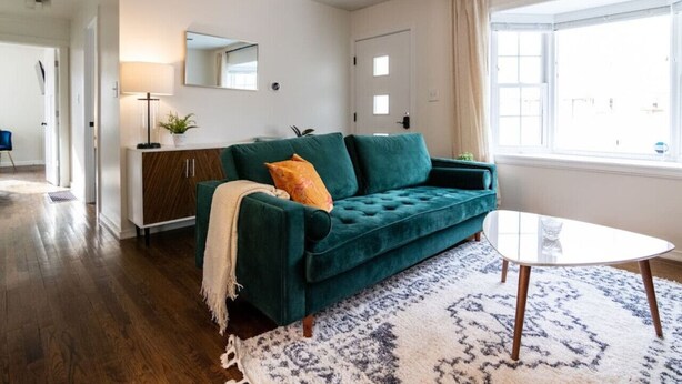 A modern living room with a teal sofa, a glass coffee table, and a patterned rug. - Juniper * Midcentury Modern 4BED Retreat Westfield (Westfield)