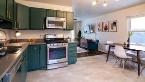 A modern kitchen with green cabinets, stainless steel appliances, and a dining area with a table and chairs. - Juniper * Midcentury Modern 4BED Retreat Westfield (Westfield)