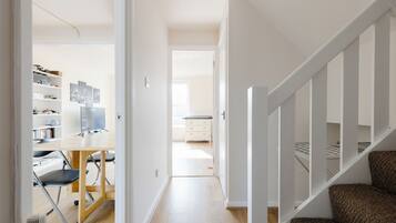 Un intérieur moderne avec un plancher en bois, un bureau avec une chaise, une bibliothèque et un escalier.