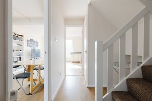 A modern interior with a wooden floor, a desk with a chair, a bookshelf, and a staircase. - Spacious 3BDR Kennington Home with Private Garden (London)