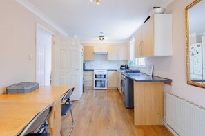 A compact kitchen with a dining area, a built-in oven, and a refrigerator. - Spacious 3BDR Kennington Home with Private Garden (London)