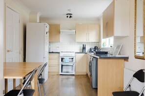Eine kleine Küche mit Kühlschrank, Herd, Backofen und Waschmaschine.