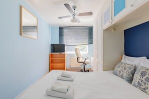 A bedroom with a bed, a desk, a chair, a ceiling fan, and a window with blinds. - Spacious 3BDR Kennington Home with Private Garden (London)